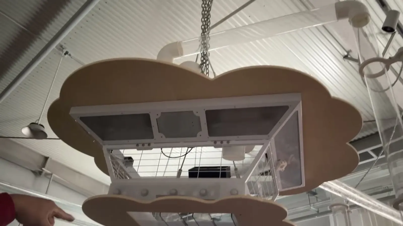 Technician hoisting a custom suspended exhibit module during on-site installation