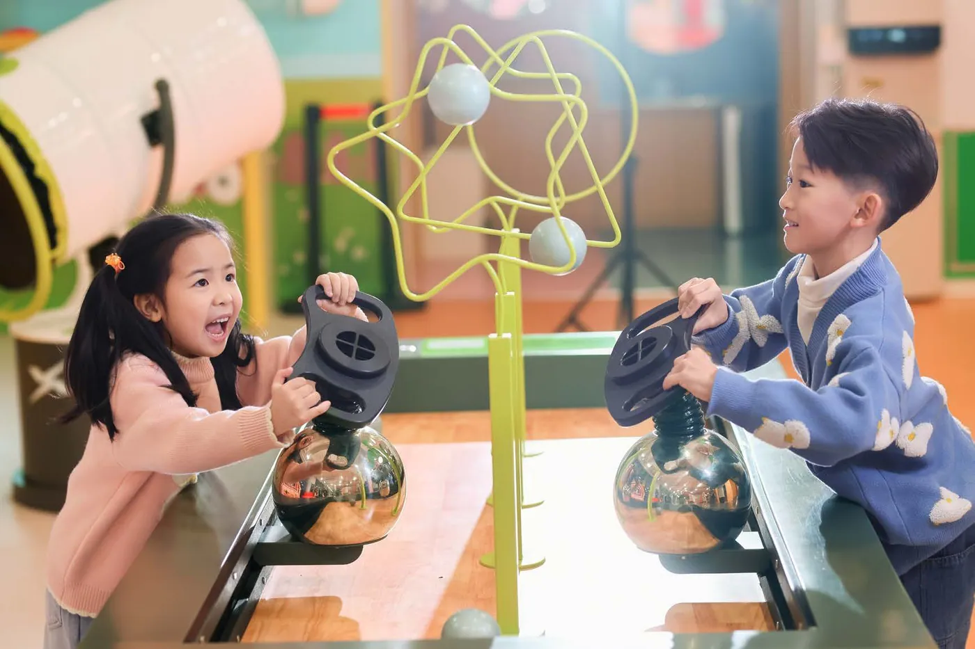 Two children exploring an interactive air-powered science exhibit at XPLOPLO