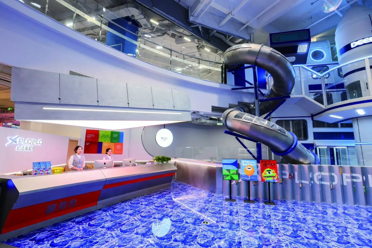 XPLOPLO reception desk and silver tube-slide feature inside Qidian Exploration Museum